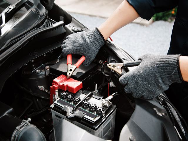Jumper clamps being fitted to a car battery's terminals
