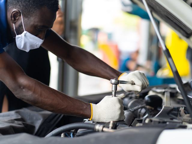 A technician working in an engine bay with a socket wrench
