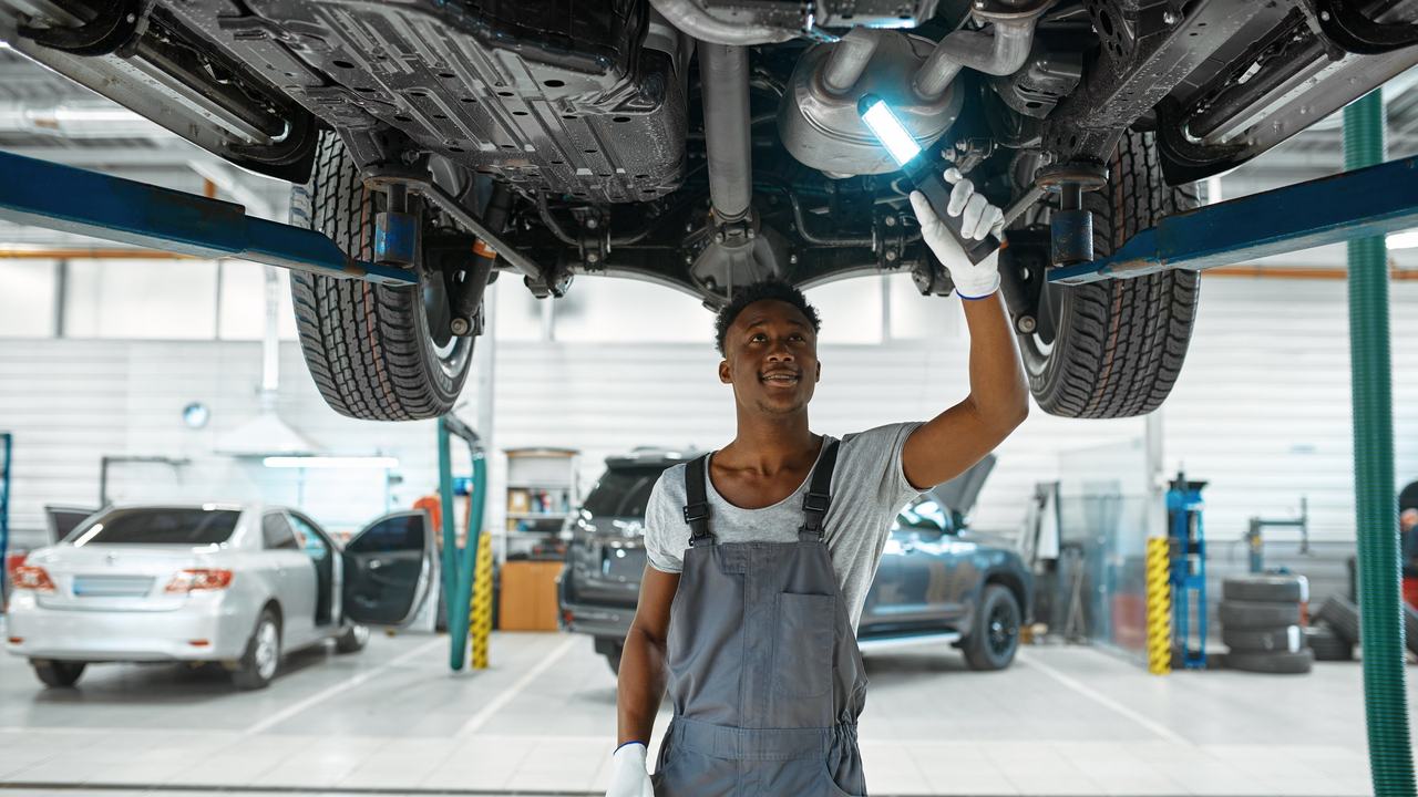 A technician inspecting the underside of a car on a workshop lift